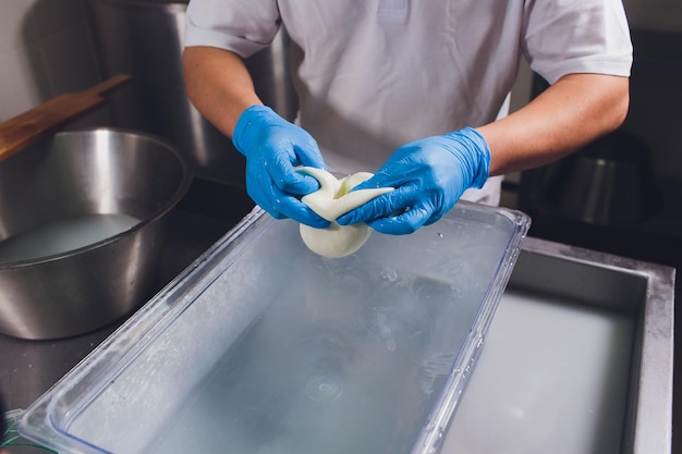 El quesero artesano corta la mozzarella con las manos