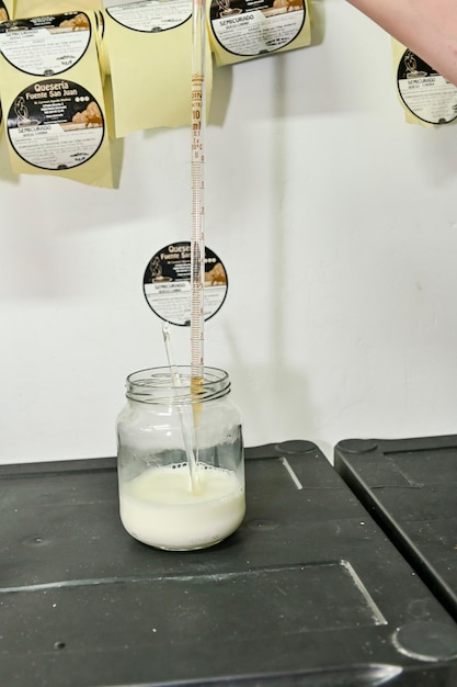 Quesero toma con el tubo de ensayo de la mano con la cuajada para la producción de queso en la lechería
