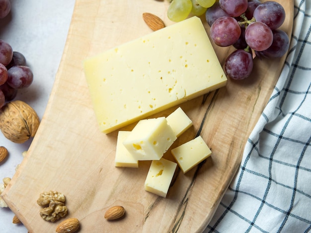 Queso con agujeros, uvas, frutos secos, Mesa de snack con aperitivos