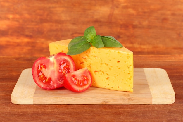 Queso, albahaca y tomate en la tabla de cortar en el espacio de madera