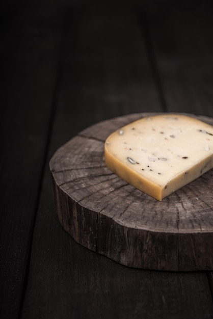 Queso amarillo con semillas en un extremo de madera de un árbol