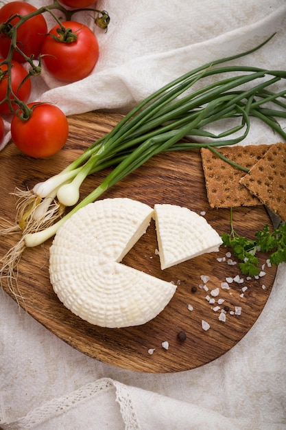 Queso blanco orgánico hecho en casa servido con tomates cebollas albahaca y pan crujiente hierbas y sal