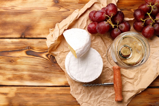 Queso blanco redondo con uvas en la mesa de madera de cerca