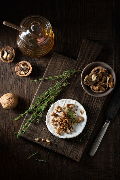 Queso brie con nueces y miel sobre una tabla de cortar de madera