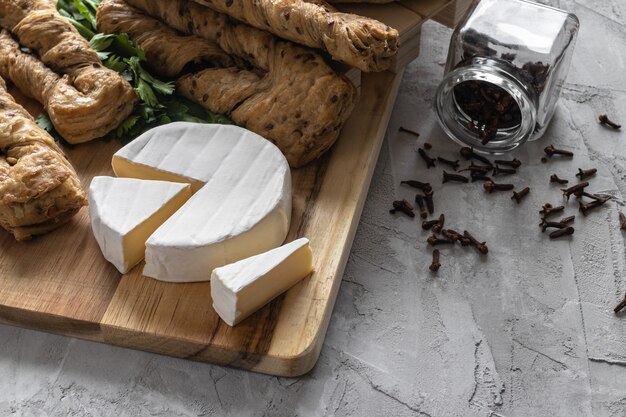 Foto queso brie con pan fresco sobre tabla de madera