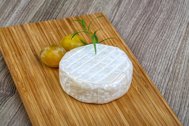 Foto queso brie redondo con ciruelas amarillas y estragón