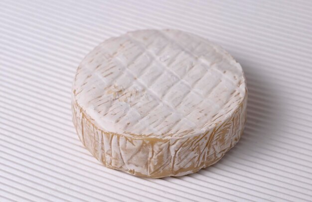 Queso brie redondo sobre un fondo ondulado blanco vista de cerca