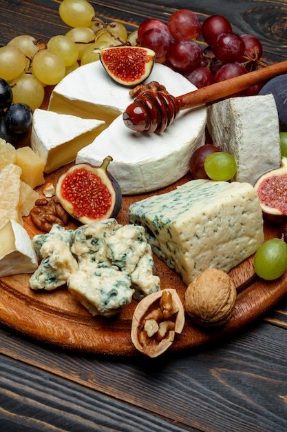 Queso Brie en una tabla de madera con higos frescos y uvas