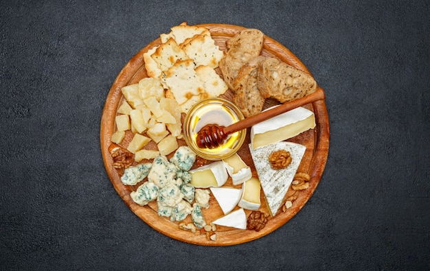 Queso Brie en una tabla de madera con pan y miel dulce