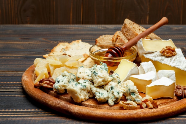 Foto queso brie en una tabla de madera con pan y miel dulce