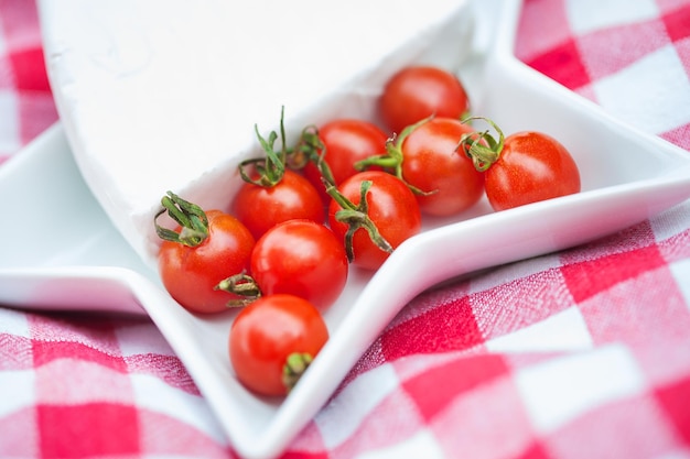 Queso brie y tomates cherry sobre mantel rojo de cerca