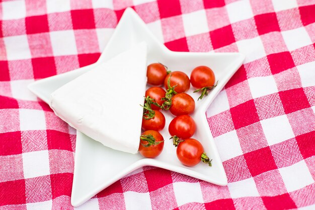 Queso brie y tomates cherry sobre mantel rojo