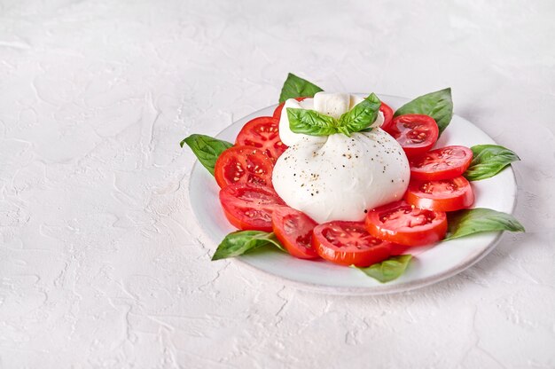 Foto queso burrata italiano tradicional elaborado con crema y leche de búfalo o vaca con albahaca y tomate