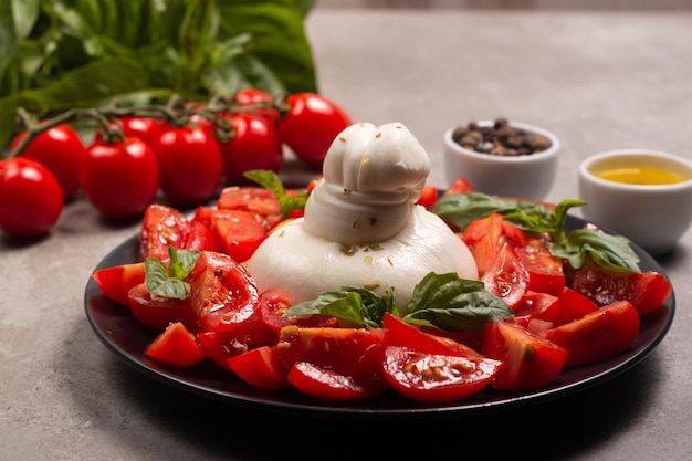 Queso burrata tradicional italiano con ensalada de delicioso tomate cherry, hojas de albahaca y aceite de oliva