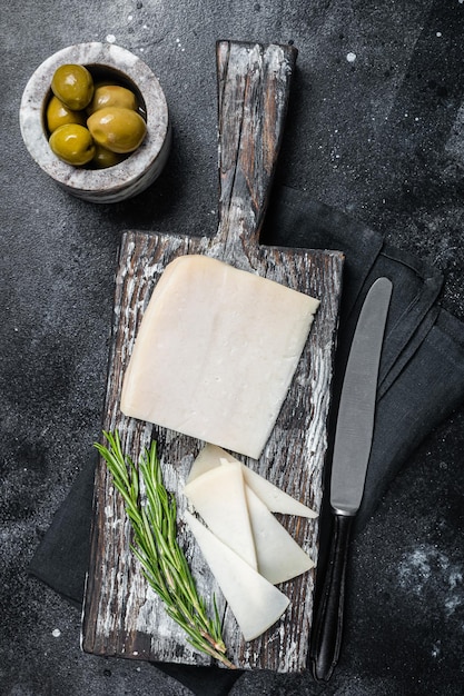 Queso de cabra holandés rebanado en una tabla de cortar de madera Fondo negro Vista superior