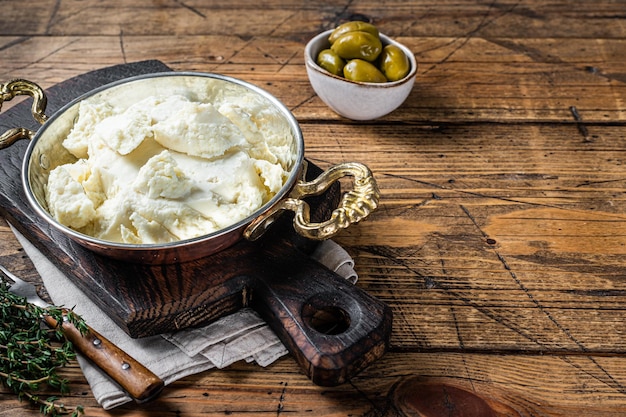 Queso de cabra y oveja en una sartén con aceitunas y romero Fondo de madera Vista superior Espacio de copia