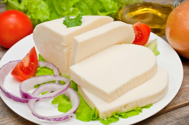 queso de cabra suave en un bol sobre una mesa de madera con verduras