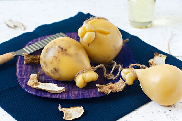 Queso Caciocavallo en un fondo de madera de la placa con el vino. Pera de queso