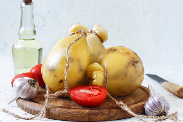 Queso Caciocavallo, tomates, ajo, aceite de oliva sobre un fondo blanco. Pera de queso