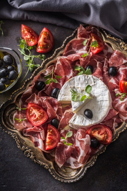 Queso camambert de prosciutto o coppa jamón tomates aceitunas y hierbas de orégano.