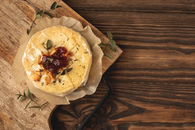 Foto queso camembert al horno, fondo de madera, espacio de copia