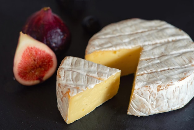 Queso camembert con higos y arándanos sobre fondo oscuro