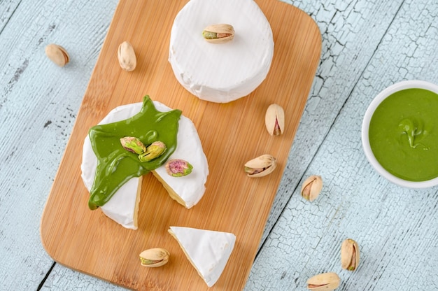 Queso camembert con mantequilla de pistacho en la tabla de cortar de madera