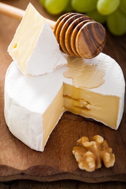 Foto queso camembert con miel de uvas y nueces sobre fondo de madera