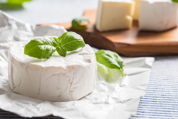 Queso camembert o brie con hojas de albahaca sobre la mesa.