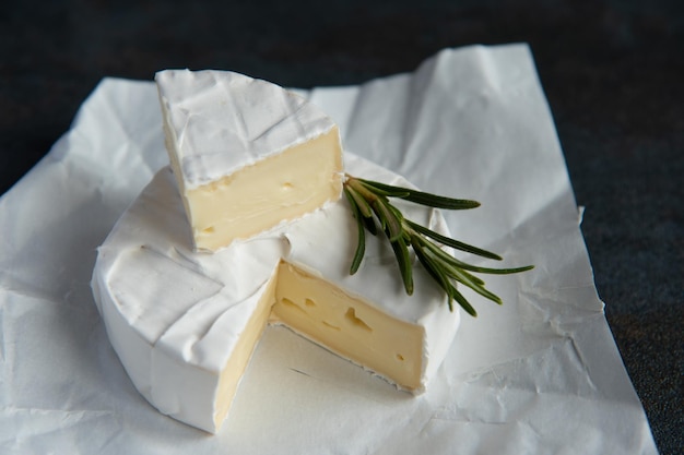 Foto queso camembert o brie con romero y pimienta sobre fondo de piedra oscura. copie el espacio. foto de estudio.