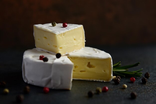 Queso camembert o brie con romero y pimienta sobre fondo de piedra oscura. Copie el espacio. foto de estudio.