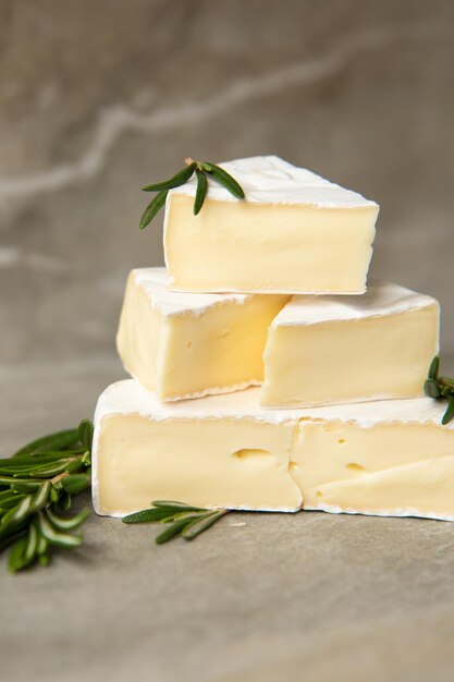 Foto queso camembert o brie con romero en tabla de cortar sobre fondo de piedra de mármol. copie el espacio. foto de estudio.