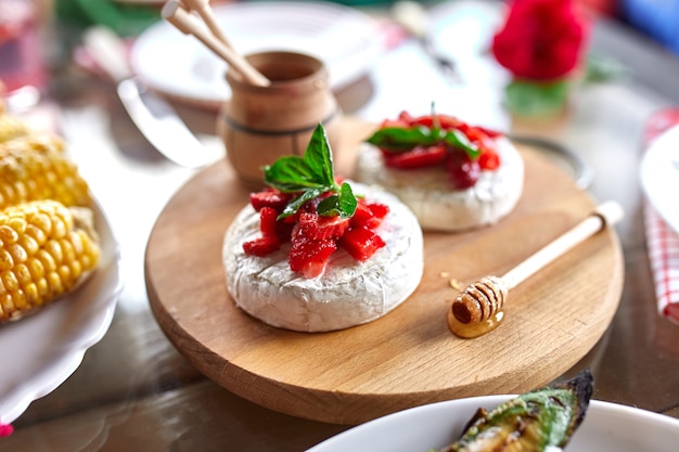 Queso camembert a la plancha con fresa, miel y hojas de albahaca, delicatessen, fondue de queso camembert en la mesa.