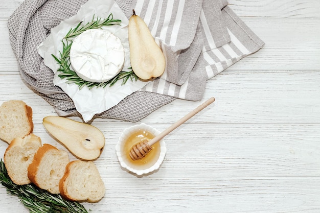 Queso camembert con ramita de pera y romero con miel sobre la mesa