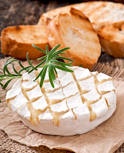 Queso Camembert y una ramita de romero sobre una mesa de madera