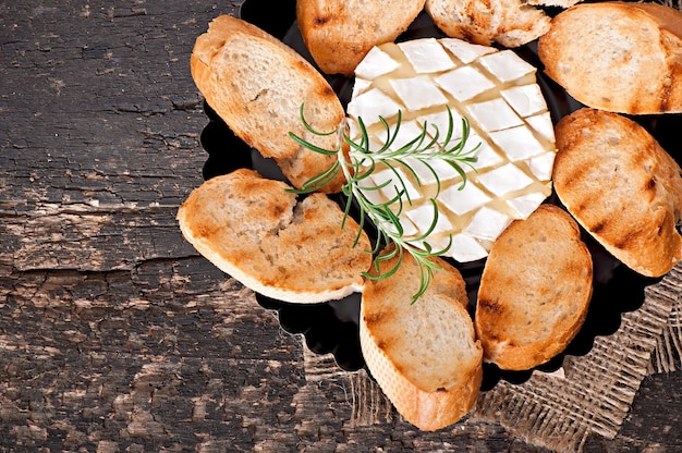 Foto queso camembert y una ramita de romero sobre una mesa de madera