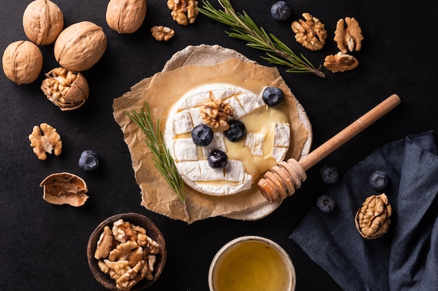 Queso camembert sobre papel blueberrys nueces miel sandwicheson sobre fondo gris italiano francés