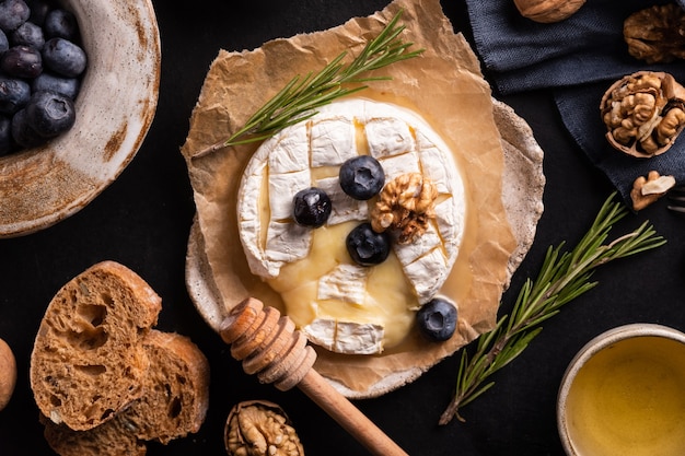 Queso camembert sobre papel blueberrys nueces miel sandwicheson sobre fondo gris italiano francés