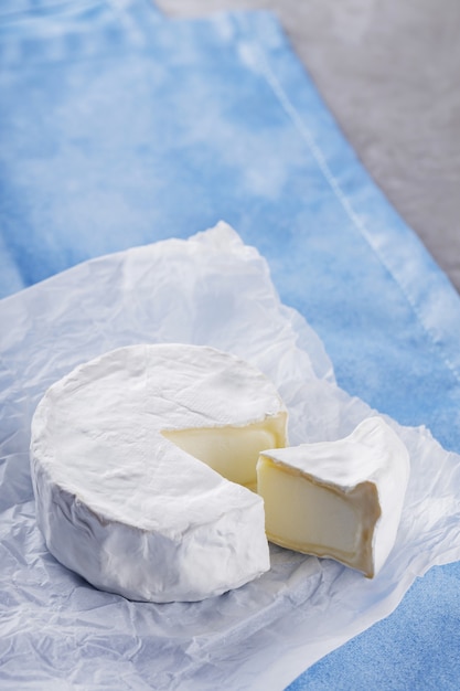 Queso camembert sobre servilleta azul. Queso blanco sobre superficie de cemento. Copia espacio