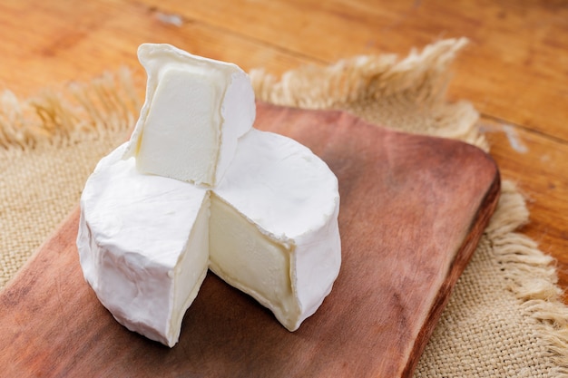 Queso camembert sobre una tabla de cortar de madera. Queso blanco sobre un fondo de madera. Copia espacio