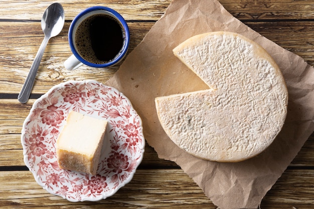 Queso Canastra artesanal de Minas Gerais, Brasil con taza de café sobre mesa de madera