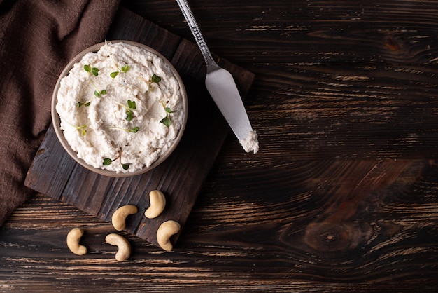 Queso crema vegano hecho de nueces anacardos fermentados en el espacio de copia de fondo de madera oscura.