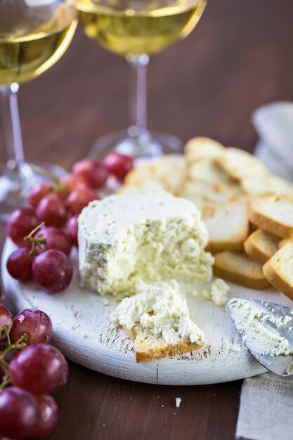 Queso cremoso de sabor suave con ajo y finas hierbas sobre una tabla de madera con galletas.