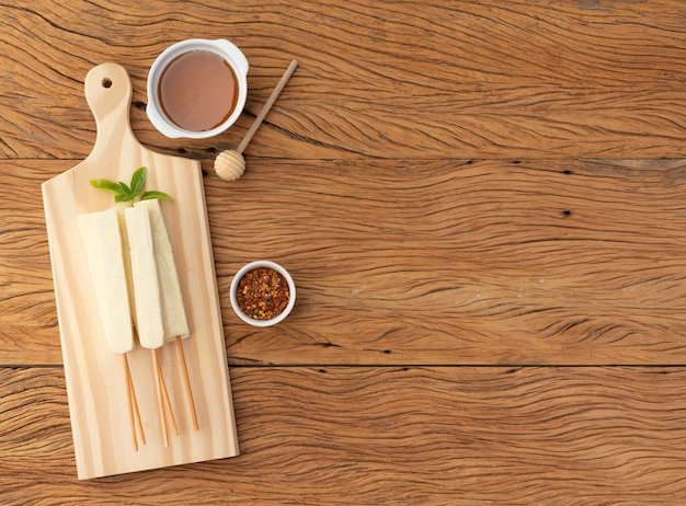 Queso cuajo o Coalho sobre una tabla de madera con jarabe de azúcar, pimienta y copie el espacio.