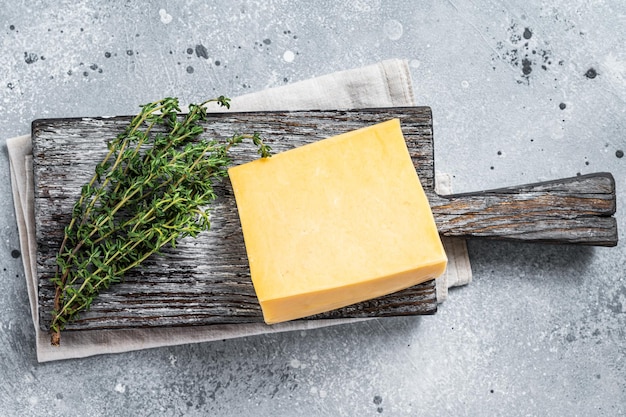 Queso duro con cuchillo en tabla de cortar de madera. Parmesano. fondo gris. Vista superior.