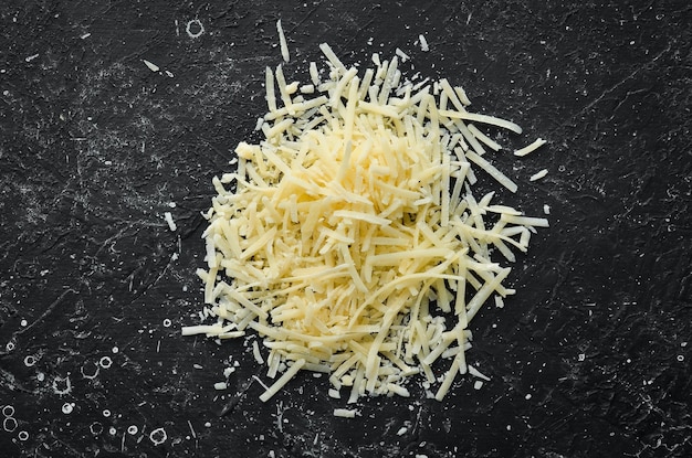 Queso duro rallado sobre un fondo de piedra negra Parmesano Vista superior Espacio libre para su texto