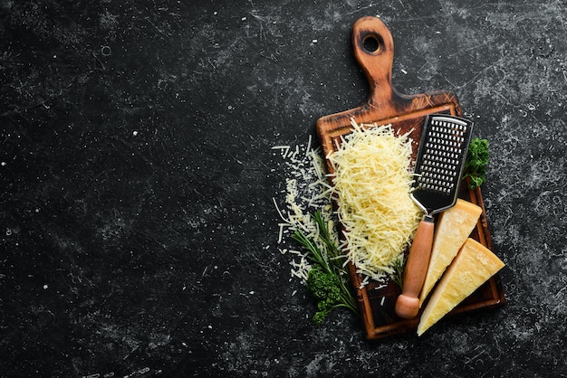 Queso duro rallado sobre un fondo de piedra negra Parmesano Vista superior Espacio libre para su texto