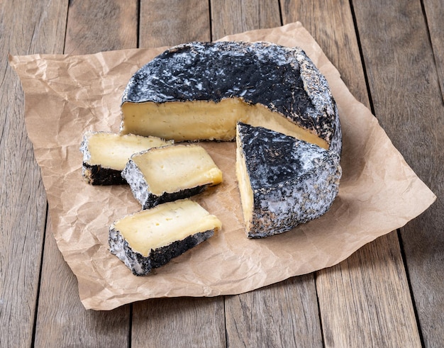 Queso envejecido al carbón con rebanadas sobre una mesa de madera