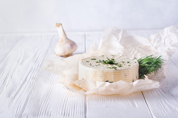 Queso en escabeche con eneldo, especias y ajo sobre un fondo de madera blanca