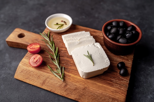 queso feta, con romero, tomates, aceitunas sobre un fondo de piedra.